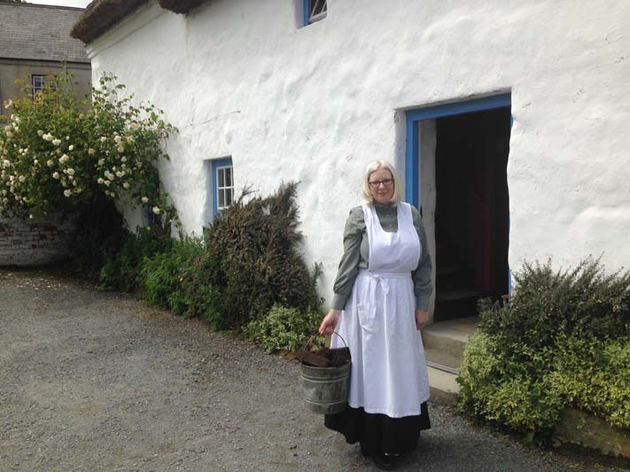 Museum volunteer in period costume bringing in turf for the fire to make soda bread